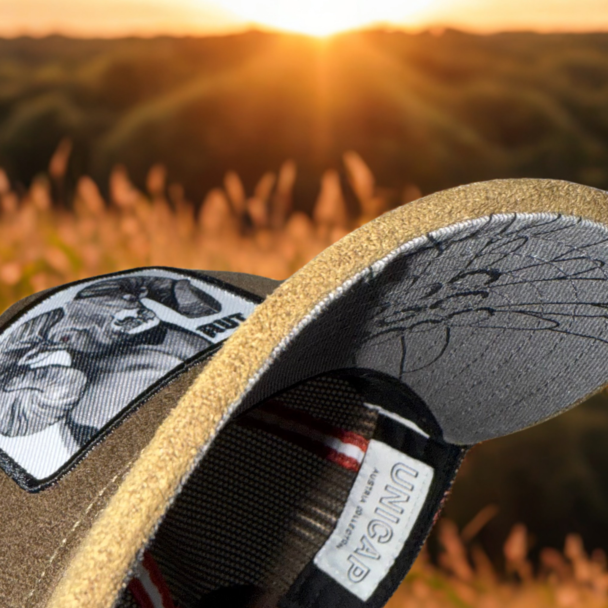 Braune Snapback-Mesh-Cap aus Österreich mit Edelweiß-Motiv am Undervisor, Austria-Label und Sonnenuntergang im Hintergrund